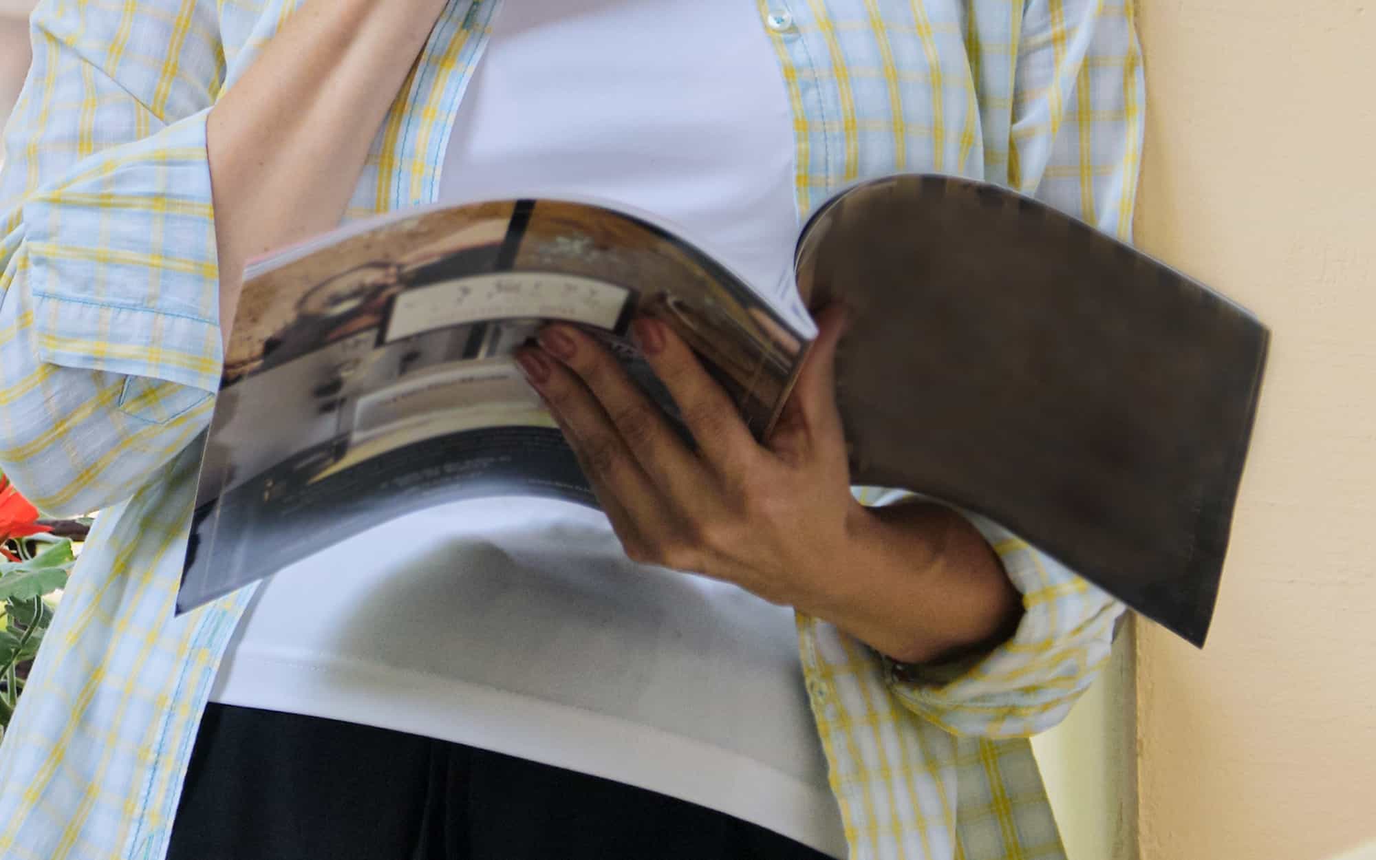 Person Reading Magazine Leaning Against Wall