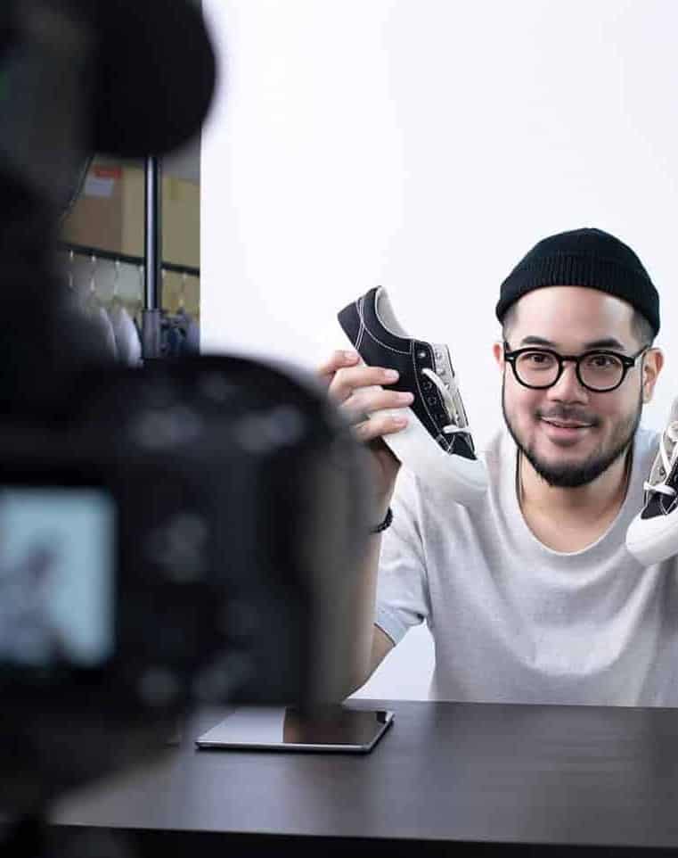 man holding shoes in front of camera, making a brand commercial