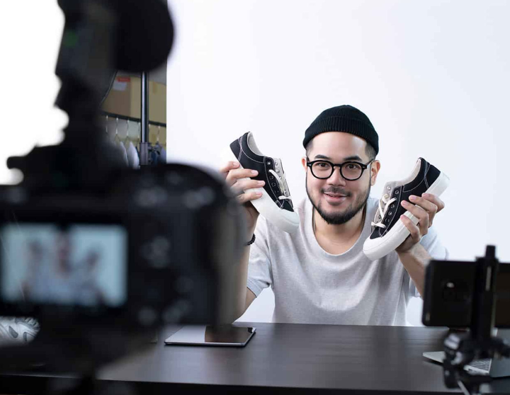 man holding shoes in front of camera, making a brand commercial