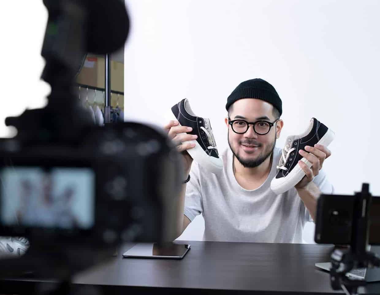 man holding shoes in front of camera, making a brand commercial