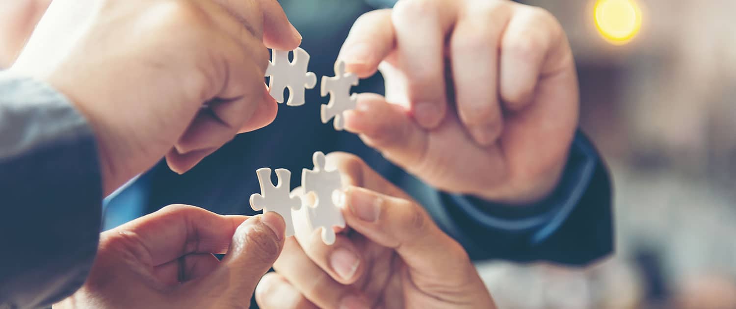 pr team holding puzzle pieces in agency office, view of hands only