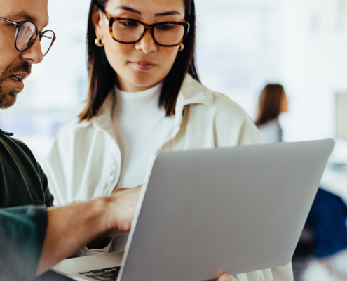 PR specialist looking at campaign on laptop with client at firm office