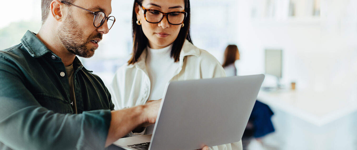 PR specialist looking at campaign on laptop with client at firm office