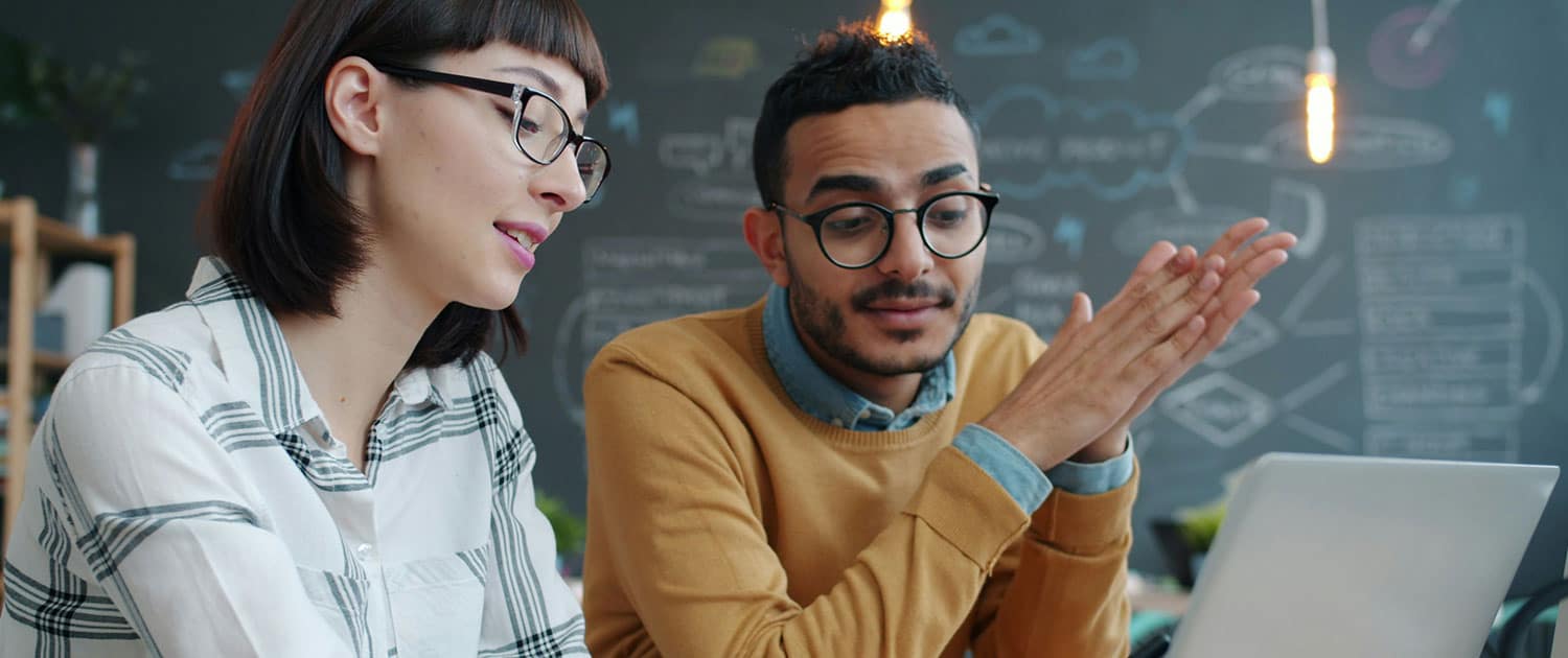 two public relations specialists discussing ad campaign looking at laptop