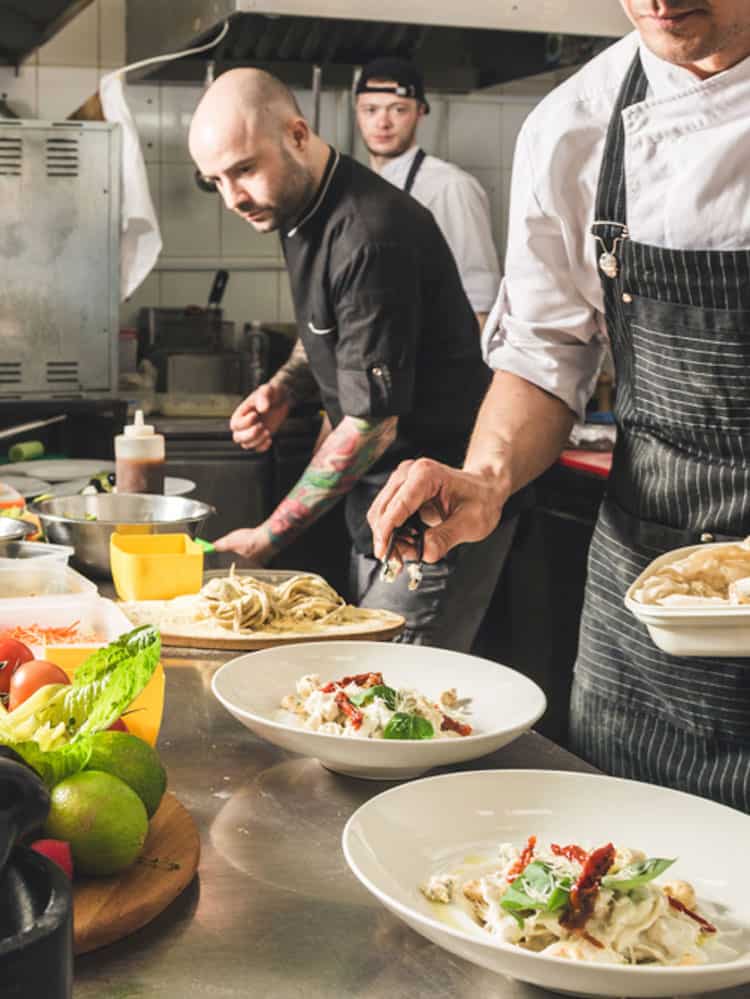 chef's in back of restaurant kitchen preparing food