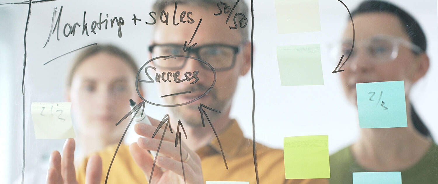 pr team in office working on pr marketing plan on clear whiteboard