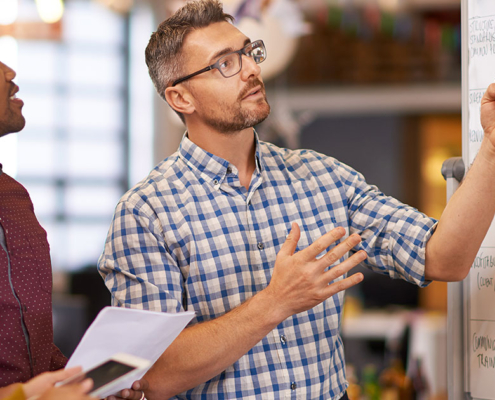 pr team in corporate office working out earned media campaign on whiteboard
