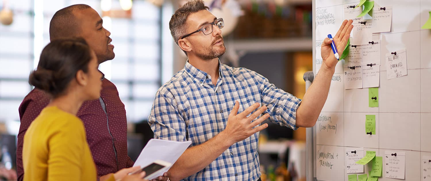 pr team in corporate office working out earned media campaign on whiteboard