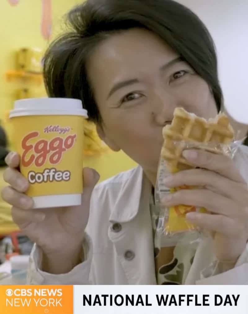 woman eating a waffle and holding up Kellogg's Eggo Coffee branded cup at pr event