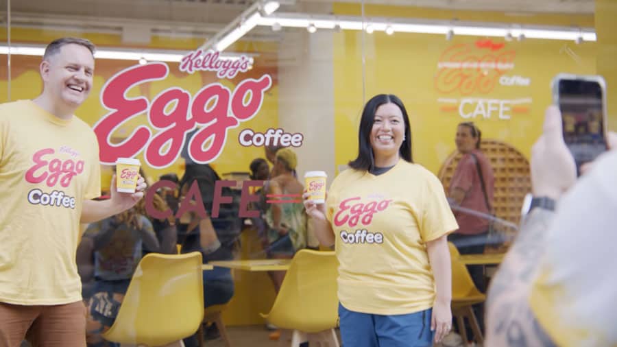 woman wearing eggo waffle branded tshirt and holding branded coffee cup, standing outside of Kellogg's Eggo Coffee event cafe