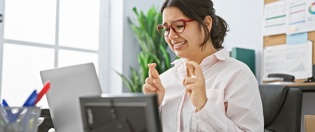 pr team member crossing fingers while looking anxiously at her laptop screen