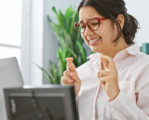 pr team member crossing fingers while looking anxiously at her laptop screen