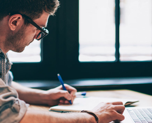 pr specialist working on earned media campaign at desk with laptop and pen pad