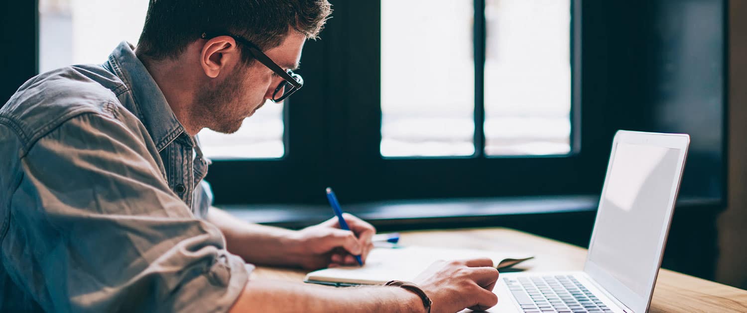 pr specialist working on earned media campaign at desk with laptop and pen pad