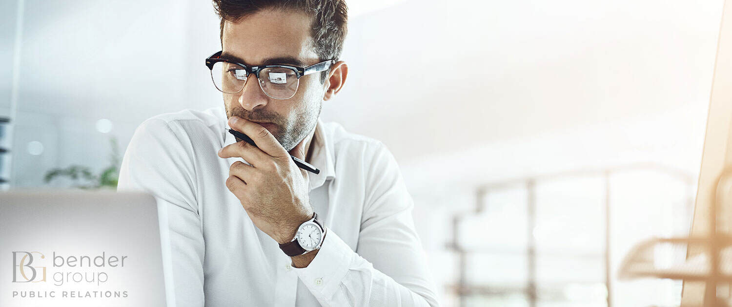 publisher looking at laptop in bright pr agency office