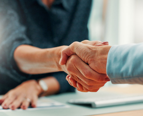 public relations account manager shaking hands with new client in office