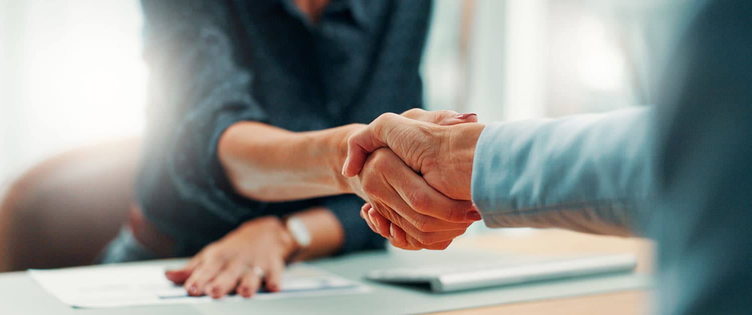 public relations account manager shaking hands with new client in office